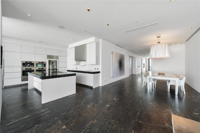 kitchen with sink, oven, a center island with sink, and white cabinets