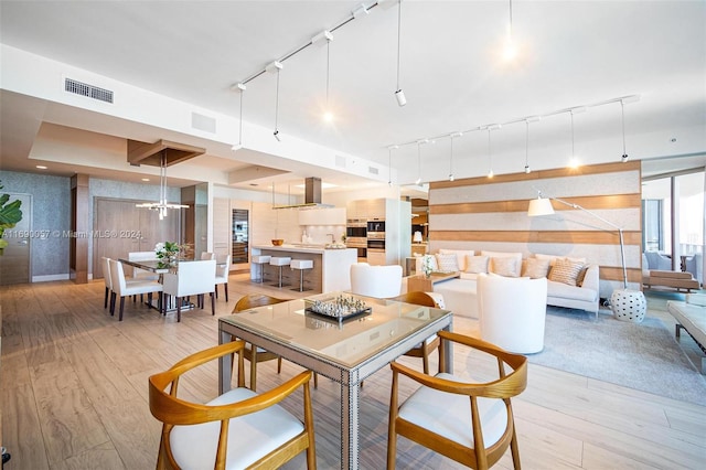 dining room featuring a chandelier, rail lighting, and light hardwood / wood-style flooring