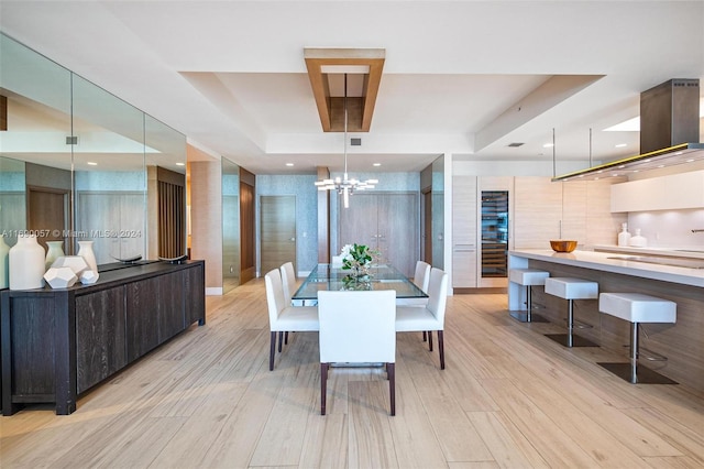 dining room featuring light hardwood / wood-style floors, an inviting chandelier, and a tray ceiling