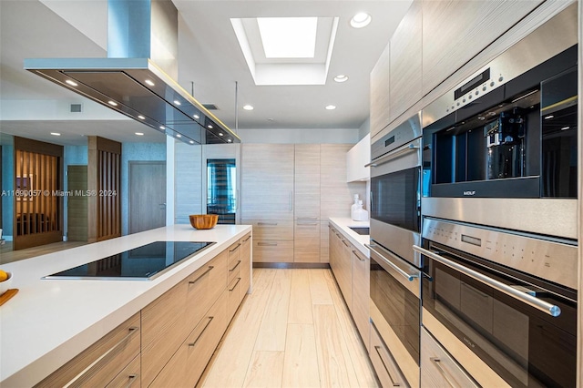 kitchen featuring a skylight, light brown cabinets, island exhaust hood, light hardwood / wood-style floors, and black electric cooktop