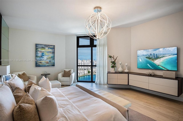 bedroom with a notable chandelier, access to exterior, light wood-type flooring, and a wall of windows