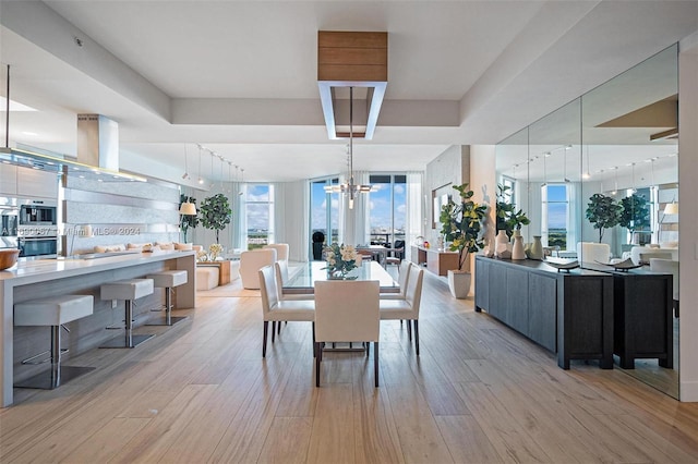 dining room with a chandelier, track lighting, and light hardwood / wood-style flooring