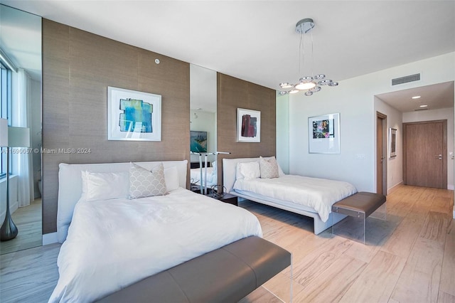 bedroom with light hardwood / wood-style flooring and a notable chandelier