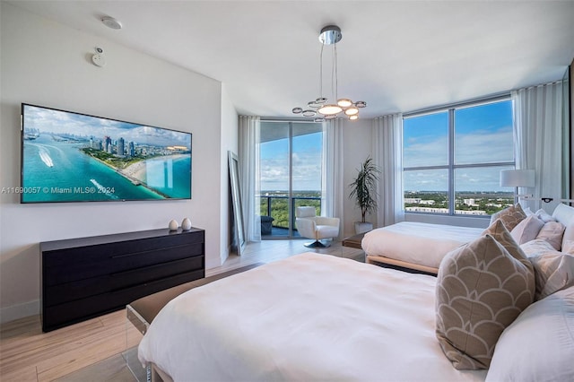 bedroom featuring a notable chandelier, expansive windows, light hardwood / wood-style floors, and access to exterior