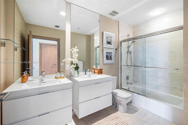 full bathroom featuring tile patterned flooring, vanity, toilet, and combined bath / shower with glass door