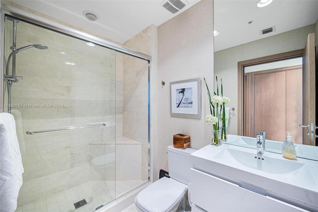 bathroom with vanity, a shower with shower door, and toilet