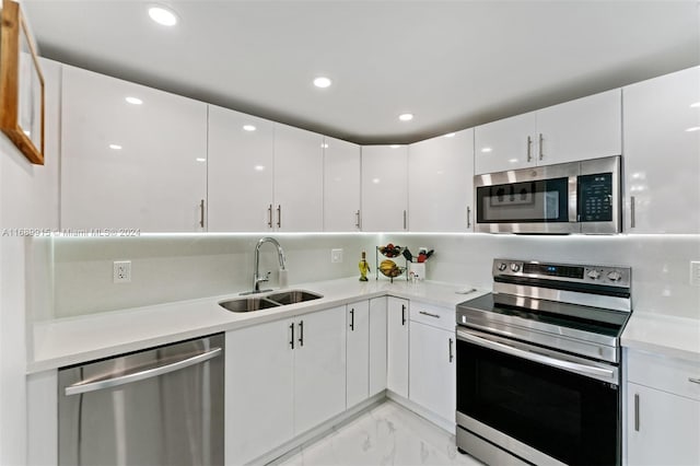 kitchen with appliances with stainless steel finishes, white cabinetry, and sink