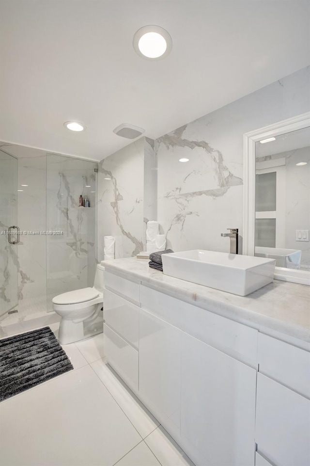 bathroom with toilet, vanity, tile patterned flooring, and a shower with door