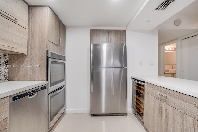 kitchen featuring beverage cooler, appliances with stainless steel finishes, decorative backsplash, and light tile patterned floors