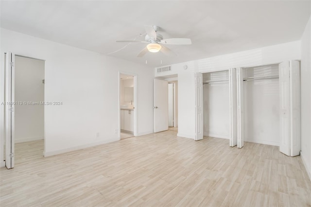 unfurnished bedroom with ensuite bathroom, multiple closets, light hardwood / wood-style flooring, and ceiling fan