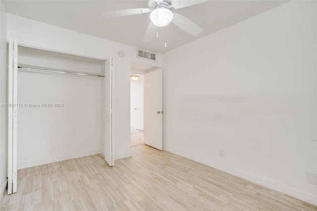 unfurnished bedroom with light wood-type flooring, ceiling fan, and a closet