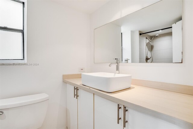 bathroom featuring vanity, toilet, and tiled shower