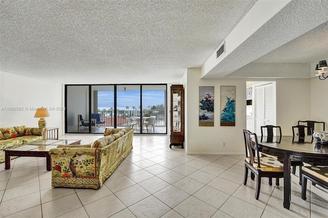 tiled living room with a textured ceiling and floor to ceiling windows