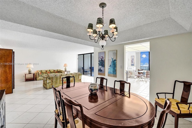 dining area featuring a chandelier, a tray ceiling, a textured ceiling, and light tile patterned floors