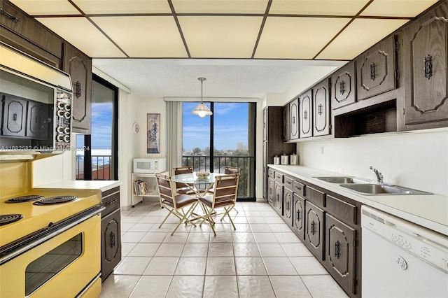 kitchen with dark brown cabinetry, white appliances, sink, and pendant lighting