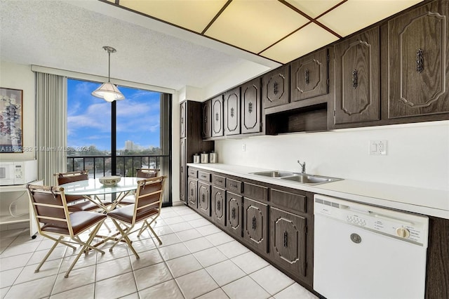 kitchen featuring dark brown cabinetry, hanging light fixtures, sink, and white dishwasher