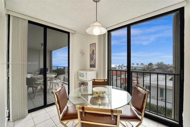 dining room featuring expansive windows, a textured ceiling, and light tile patterned floors