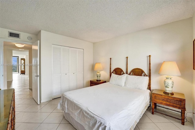 bedroom featuring light tile patterned flooring, a textured ceiling, and a closet