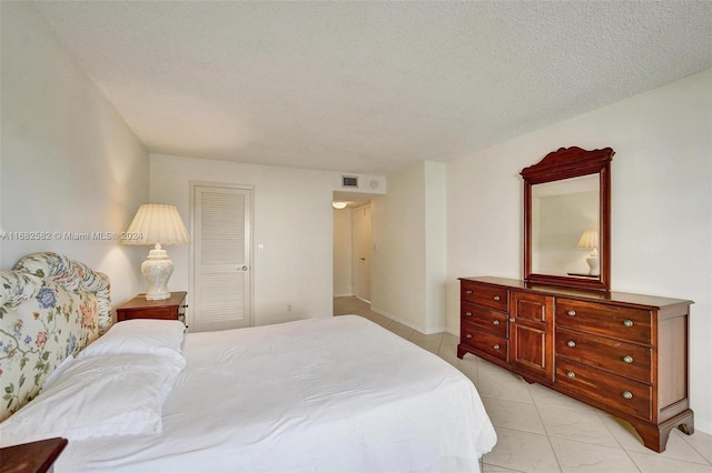 tiled bedroom featuring a textured ceiling and a closet