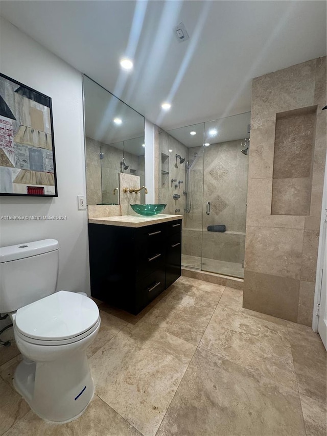 bathroom with toilet, vanity, and a shower with door