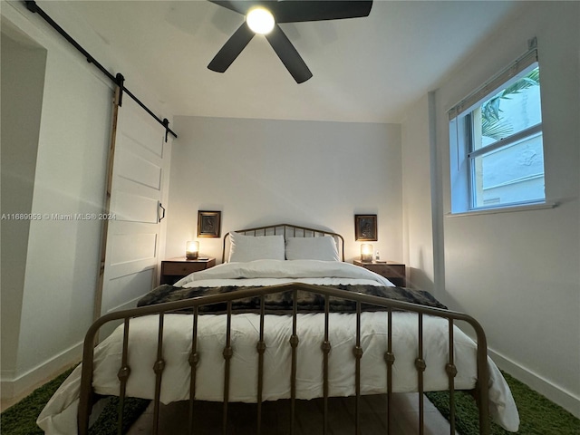 bedroom with a barn door and ceiling fan