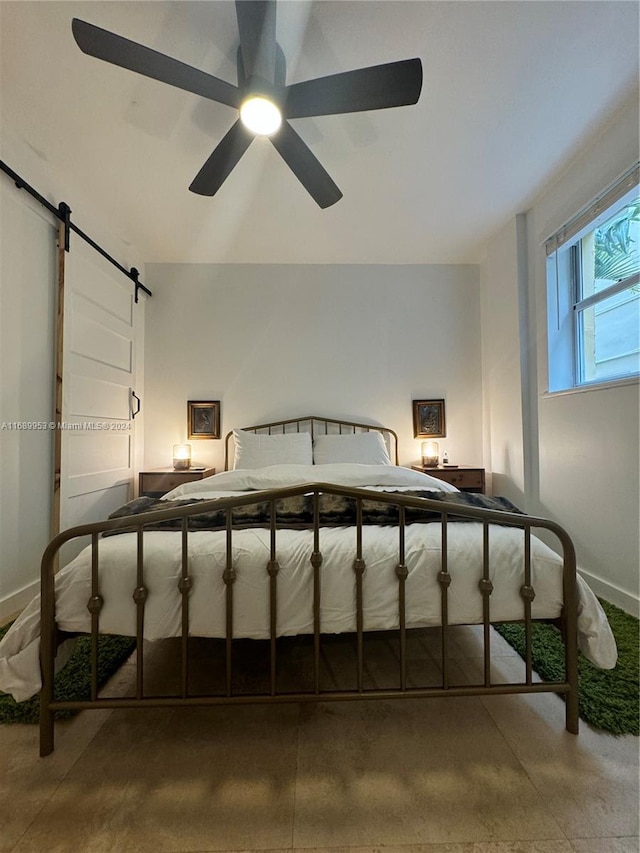 bedroom with a barn door, concrete flooring, and ceiling fan