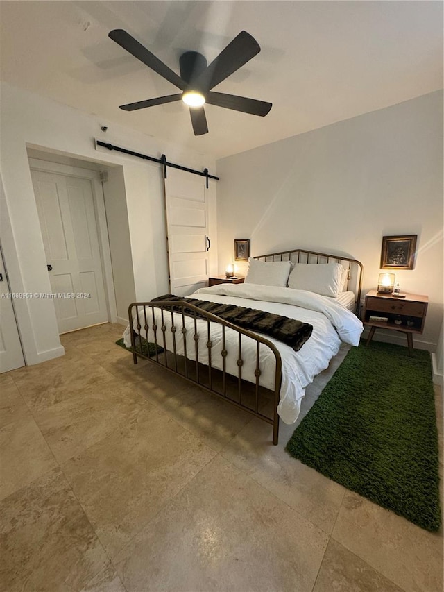 bedroom with a barn door and ceiling fan