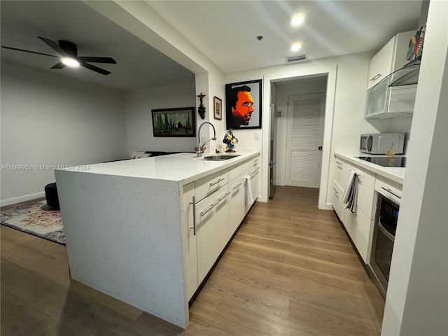 kitchen featuring stainless steel appliances, light hardwood / wood-style floors, white cabinetry, sink, and ceiling fan