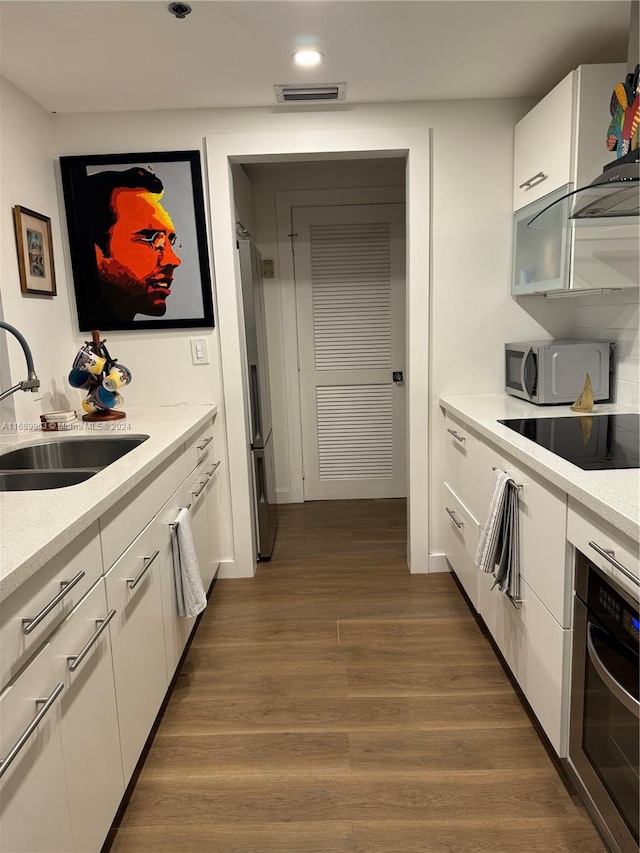 kitchen featuring stainless steel appliances, white cabinetry, sink, ventilation hood, and dark hardwood / wood-style flooring