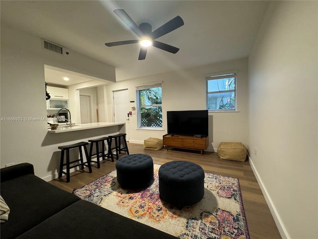 living room featuring plenty of natural light, dark hardwood / wood-style floors, ceiling fan, and sink