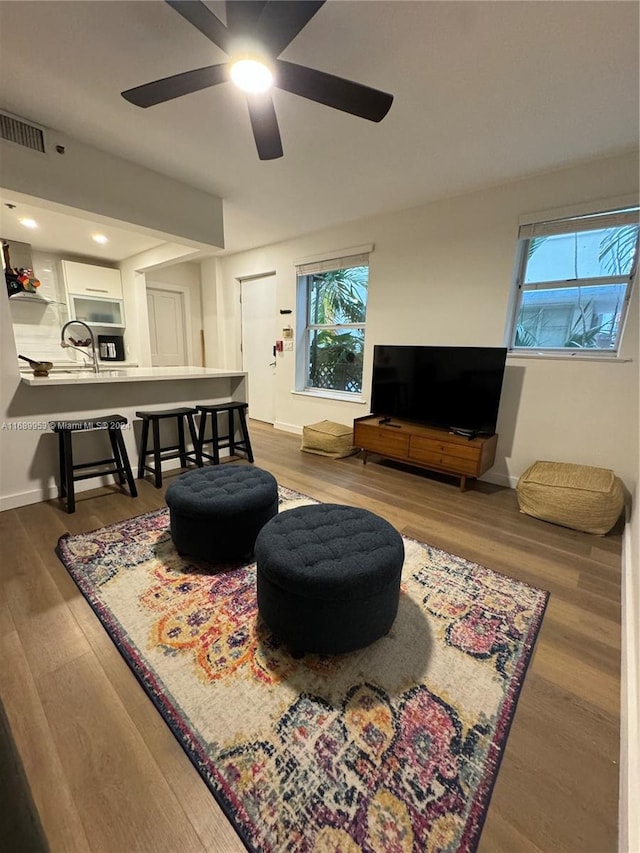 living room with a wealth of natural light, wood-type flooring, and ceiling fan