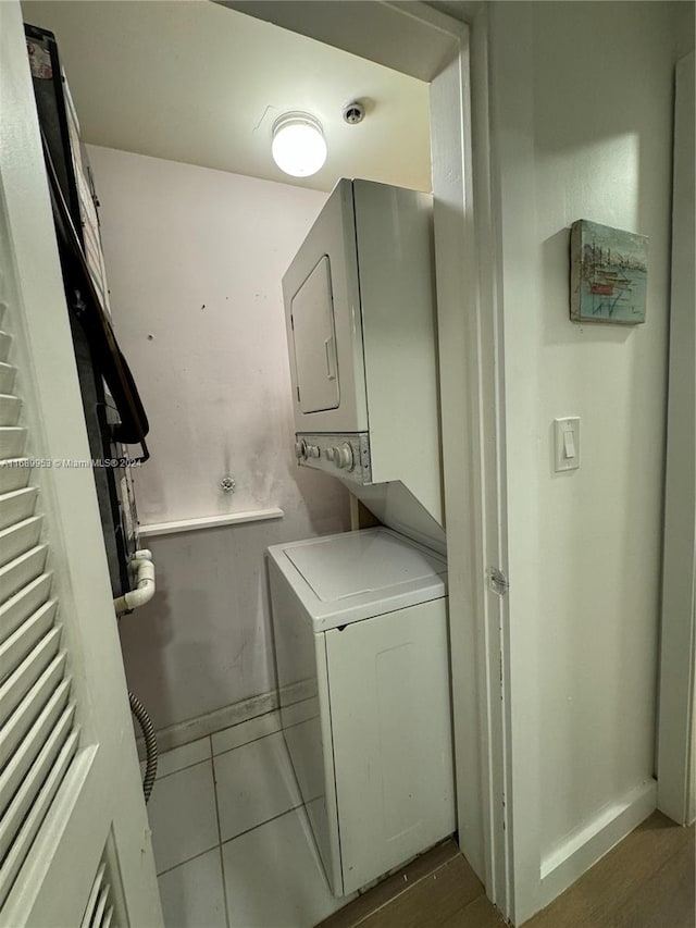 laundry room featuring tile patterned floors and stacked washer and dryer