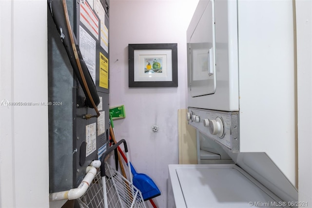 laundry room with stacked washer / drying machine and heating unit