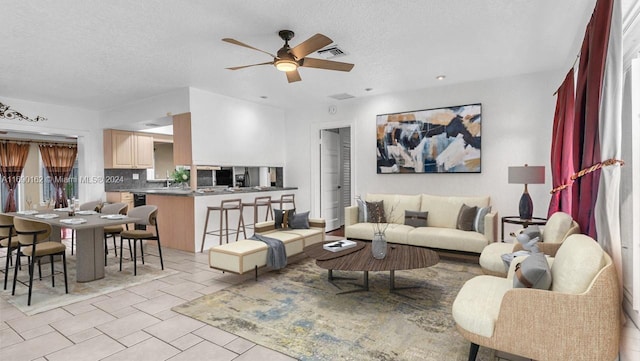 living room featuring ceiling fan and a textured ceiling