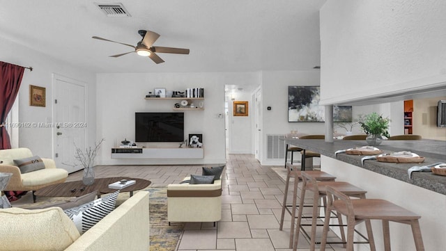 living room with ceiling fan, light tile patterned floors, and a textured ceiling