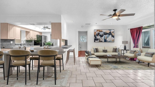 interior space featuring decorative backsplash, light brown cabinets, a textured ceiling, and ceiling fan