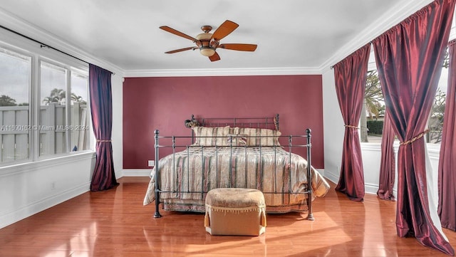 bedroom with hardwood / wood-style floors, ceiling fan, and multiple windows