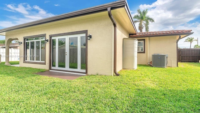 rear view of property featuring french doors, a yard, and central AC