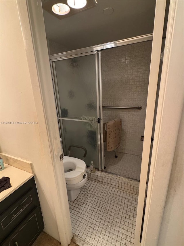 bathroom with toilet, an enclosed shower, vanity, and tile patterned floors