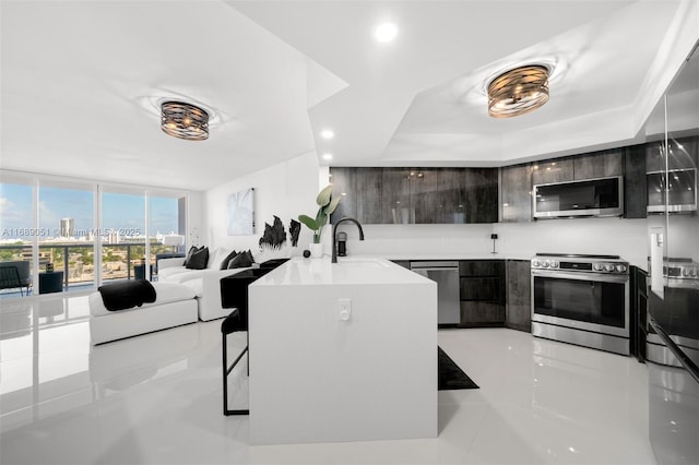 kitchen featuring light countertops, appliances with stainless steel finishes, a sink, modern cabinets, and a peninsula