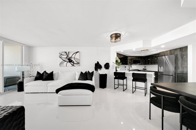 kitchen with sink, light tile patterned floors, a tray ceiling, kitchen peninsula, and stainless steel appliances