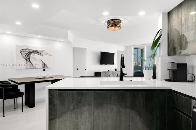 kitchen featuring recessed lighting, light countertops, a sink, and a peninsula