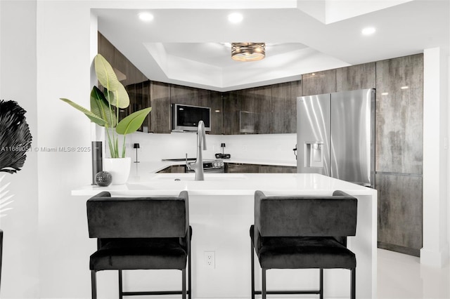 kitchen featuring stainless steel fridge, light countertops, a breakfast bar area, and modern cabinets