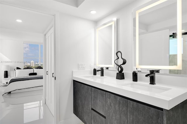 ensuite bathroom with double vanity, connected bathroom, a sink, and recessed lighting