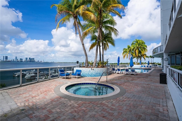 pool featuring a view of city, a community hot tub, a patio, and a water view