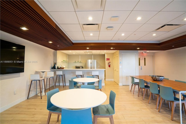 dining area with recessed lighting, baseboards, a bar, and light wood finished floors