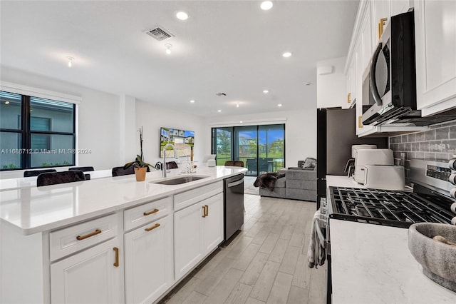 kitchen featuring appliances with stainless steel finishes, sink, light stone counters, and white cabinets