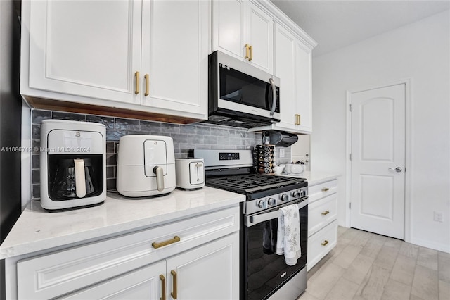 kitchen featuring light hardwood / wood-style floors, light stone counters, white cabinets, tasteful backsplash, and appliances with stainless steel finishes