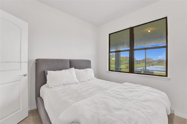 bedroom with light hardwood / wood-style floors and a water view