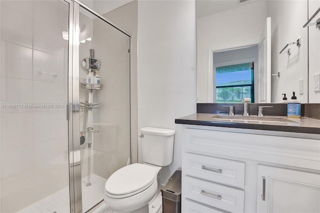 bathroom featuring toilet, vanity, and a shower with door